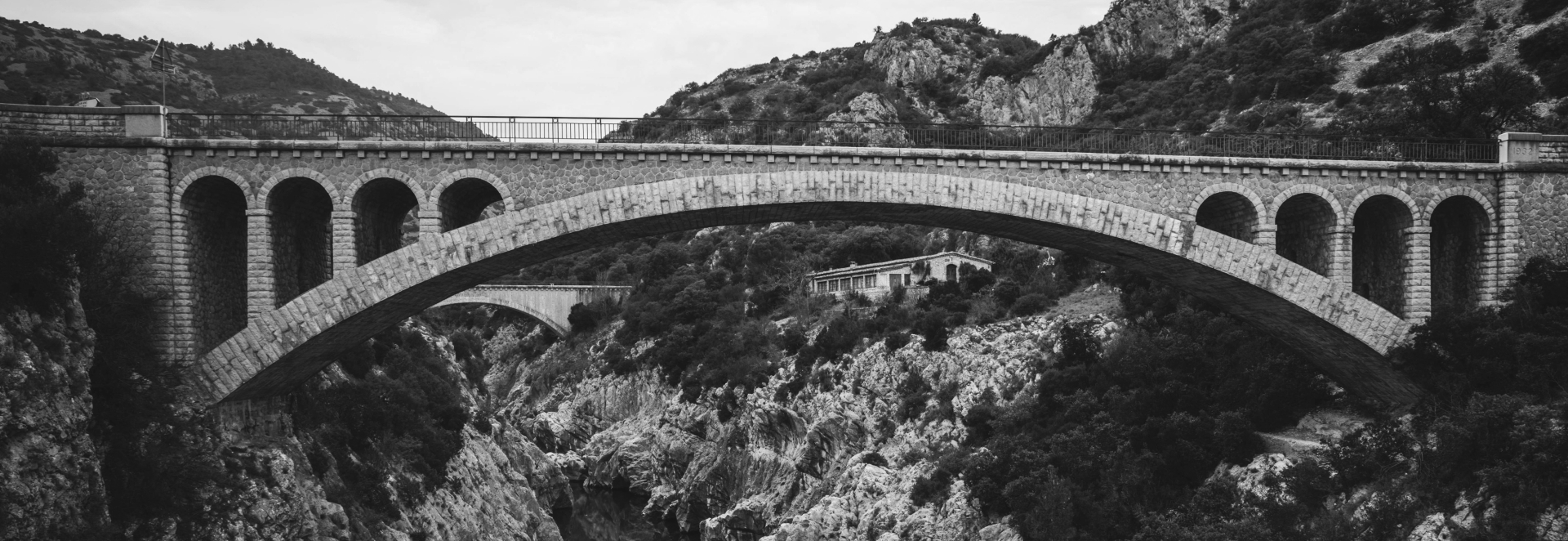 Black-and-white photograph of an arched stone bridge over a gorge